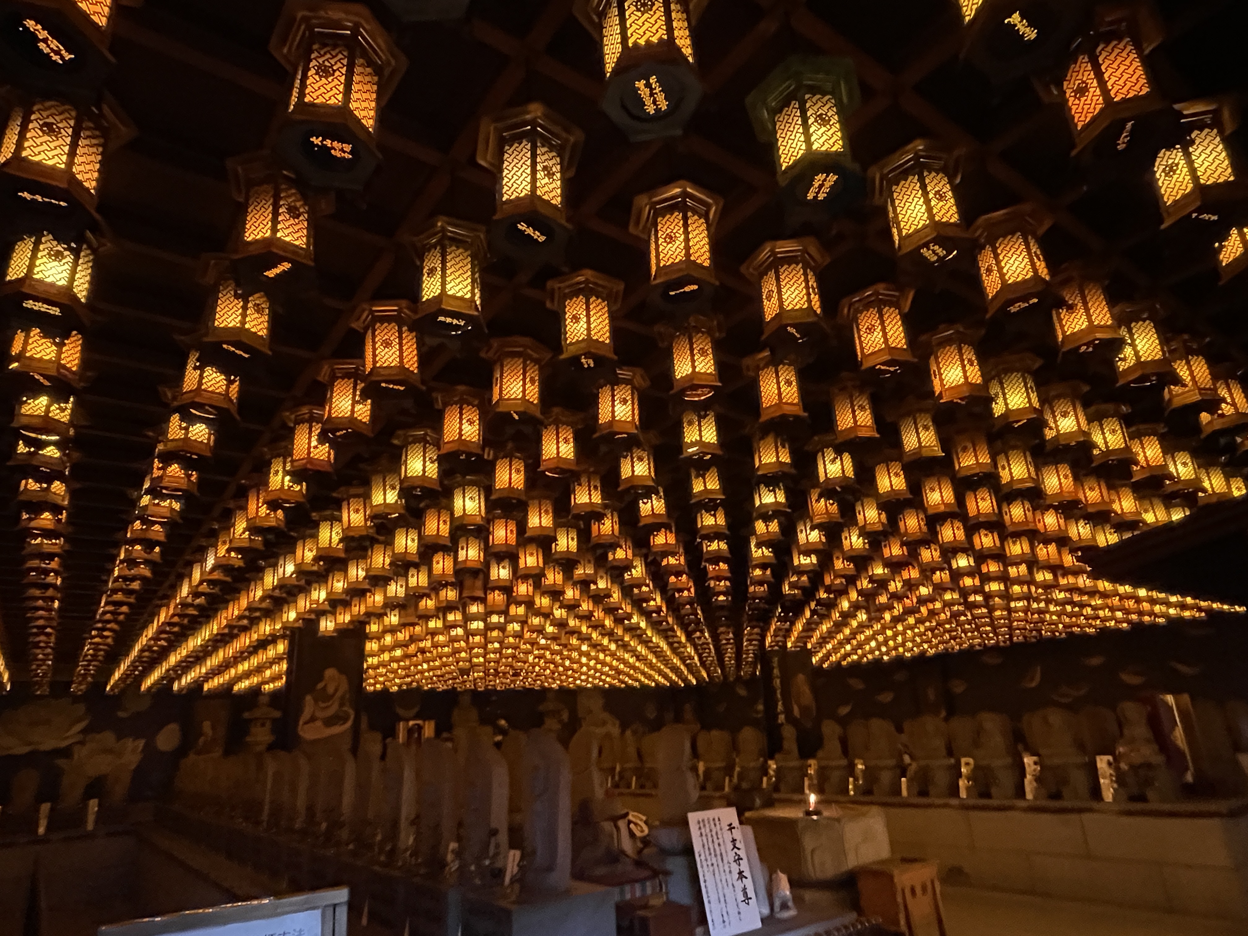 Hundreds of glowing golden lanterns hanging from the ceiling of Daishoin Temple on Miyajima Island — an extraordinary hidden sight